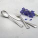 Arcoroc stainless steel dessert spoon with flowers on a table with silverware.