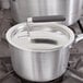 A Vollrath Wear-Ever aluminum pot lid with a black handle on a pot.