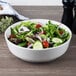 A white Villeroy & Boch porcelain salad bowl filled with salad on a table.