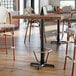 A Lancaster Table & Seating bar height table base with a foot ring on a table in a room.