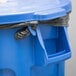 A blue Rubbermaid BRUTE trash can with a black plastic bag hanging from it.