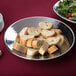 A piece of bread on a round hammered stainless steel bowl.