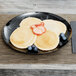 A WNA Comet black plastic plate with pancakes, strawberries, and blueberries.
