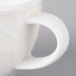 A close-up of a white Villeroy & Boch porcelain cup with a handle.