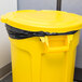 A yellow Rubbermaid BRUTE trash can with a black lid and bag.