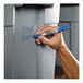 A hand using a Sharpie blue fine point marker to write on a grey container.