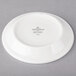 A Villeroy & Boch white porcelain saucer with a white rim and black text on it.