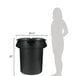 A woman standing next to a black Rubbermaid trash can with a black lid.