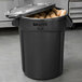 A black Rubbermaid BRUTE trash can full of potatoes.