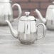 A mirror-finished stainless steel Vollrath Orion teapot on a table.