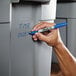 A hand writing "Sharpie" in blue on a grey container.