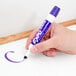 A hand holding a purple Expo dry erase marker.