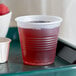 A Dart Conex translucent plastic cup with a red drink on a table.