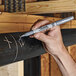 A hand using a Sharpie metallic marker to write on a pipe.
