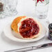 A CAC scalloped edge china plate with a piece of bread and jam on it.