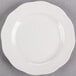 A CAC ivory china plate with a scalloped edge on a gray surface.