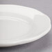 A close-up of a CAC ivory scalloped edge china plate with a small rim.