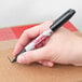 A hand holding a black Sharpie Pro marker over a box.