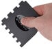 A hand holding a black Lodge grill scraper with a red logo.