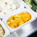 A white Cambro food pan with a tray of food, including broccoli and peppers.