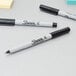A close-up of a black Sharpie permanent marker with a white cap.