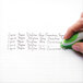 A hand using Paper Mate Liquid Paper to correct handwritten text.