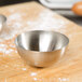 A stainless steel hemisphere mold in a silver bowl on a wood surface.