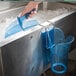 A hand using a blue San Jamar ice scoop holder to scoop ice.