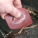 A person using a red Lodge pan scraper to clean a frying pan.