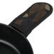 A black frying pan with a Lodge camouflage handle cover on the handle.