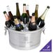 A silver Franmara Cornucopia cooler filled with ice and wine bottles on a table.