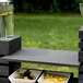 A black wood Vollrath short wide shelf holding food on a table.