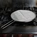 A Lodge splatter screen on a pan on a stove.