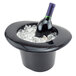 A bottle of wine in a black hat shaped wine bucket filled with ice.