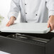 A chef holding a Vollrath full size cold pack on a white surface.