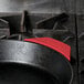 A red Lodge silicone handle holder on a black cast iron pan.