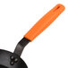 An orange Lodge silicone handle holder on a black frying pan handle.