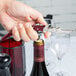 A hand using a red Pullparrot Waiter's Corkscrew to open a wine bottle.