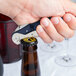 A hand using a Pullparrot Waiter's Corkscrew with a blue handle to open a bottle of beer.