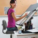 A woman sitting at a desk drawing on a drawing board.