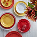 A close up of a red Tuxton Concentrix China plate with two cookies on it.