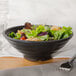 A bowl of salad with shrimp and lettuce in a black matte melamine bowl.