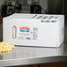 A white box of LouAna Butter Flavored Canola Popping Oil on a table.