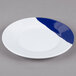 A close-up of a white melamine plate with navy blue and white stripes on the rim.