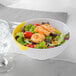 A white melamine bowl filled with salad, shrimp, and tomatoes.