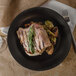 A GET Nara black melamine plate with meat and vegetables on it with a fork and knife.