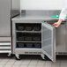 A person opening the door to a Beverage-Air worktop refrigerator.