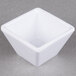 An American Metalcraft white square melamine sauce cup on a grey surface.