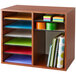 A Safco cherry wood file organizer on a wooden shelf with spiral notebooks and different colored papers.