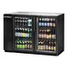 A True black glass door back bar refrigerator with bottles of beer inside.